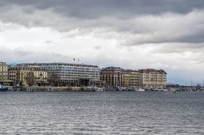 Sea by buildings against sky in city