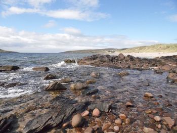 View of rocky beach against cloudy sky