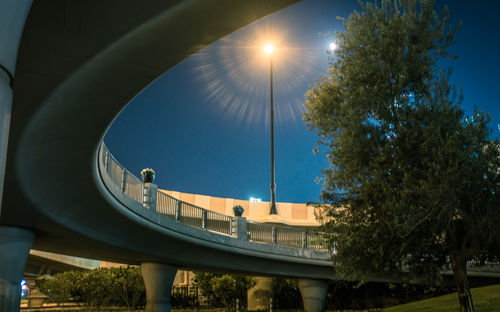 Low angle view of tree by illuminated bridge in city at night