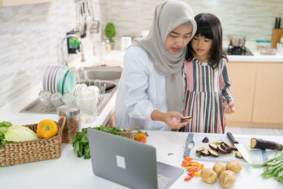 Mother and daughter standing in kitchen