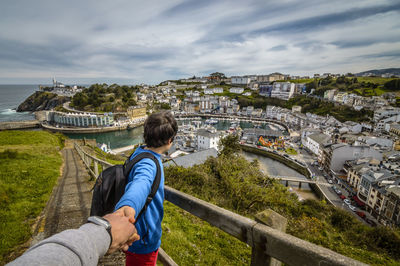 Cropped image of father with son looking at cityscape from mountain against sky