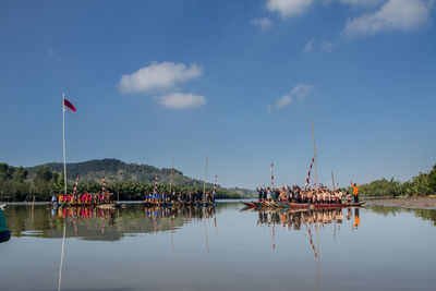 People sailing in lake against sky