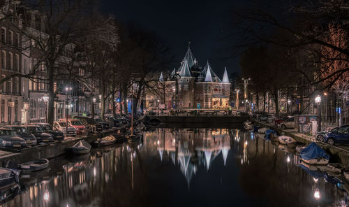 Illuminated buildings by river in city at night