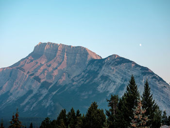 Low angle view of snowcapped mountains against clear blue sky