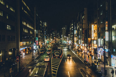 Illuminated road amidst building in city at night