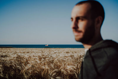 Portrait of young man looking at sea against sky