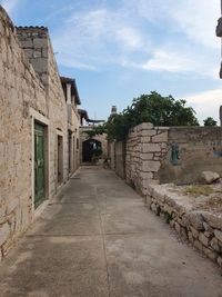 Footpath amidst old buildings against sky