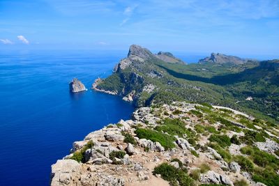 High angle view of sea and mountains against blue sky