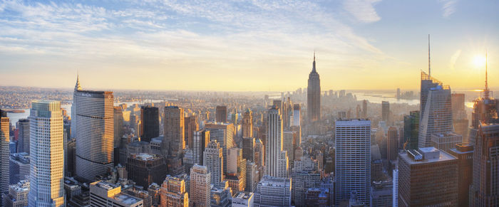 Aerial view of modern buildings in city against sky during sunset
