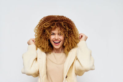 Portrait of young woman standing against white background