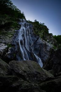 Low angle view of waterfall on rocks