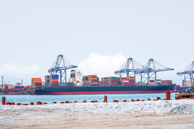 Cranes at commercial dock against sky