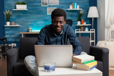 Young man using mobile phone while sitting on table