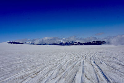 Scenic view of snow covered land against blue sky