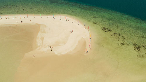 Luli island and sandy beach with tourists, sand bar surrounded by coral reef and blue sea 