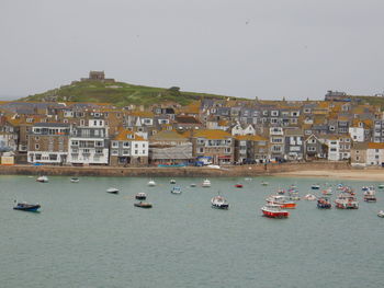 Sailboats in sea by buildings against clear sky