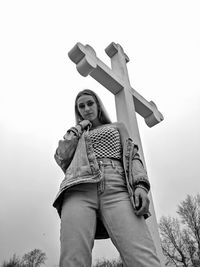 Low angle portrait of woman standing against sky