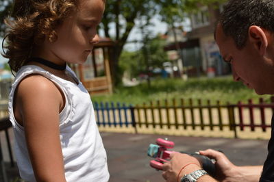 Girl looking at her father repairing roller skating in park