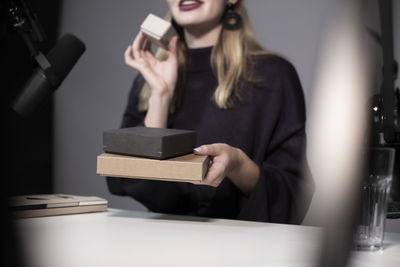 Midsection of businesswoman showing product while recording on camera