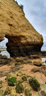 Rock formation on sea shore against sky