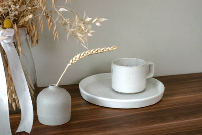 A glass decoration and ceramic jars are on a wooden table in a room.