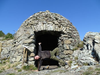 Man standing on rock against clear blue sky