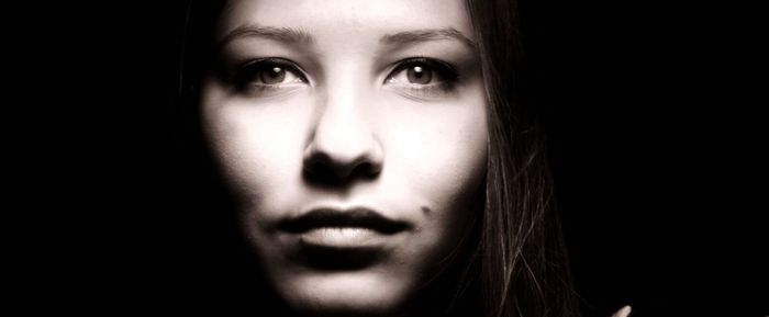 Close-up portrait of beautiful woman against black background