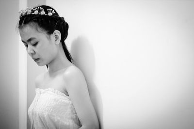 Side view of bride wearing tiara while standing by wall