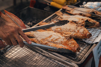 Cropped hand of person preparing food on barbecue grill