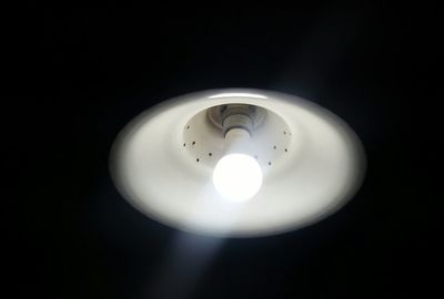 Low angle view of illuminated light bulb against black background