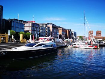 Sailboats moored on river in city against sky