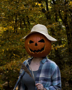  woman in plaid wearing carved pumpkin in a colorful fall setting