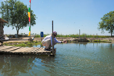 Man by lake against sky