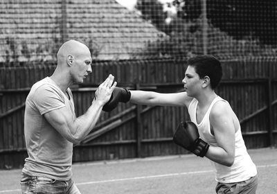 Side view of young male trainer teaching boxing to boy