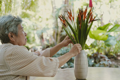 Smiling woman sitting by table with potted plant