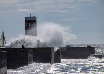 Big wave crashing over the wall at farolim da barra do douro lighthouse in porto, portugal