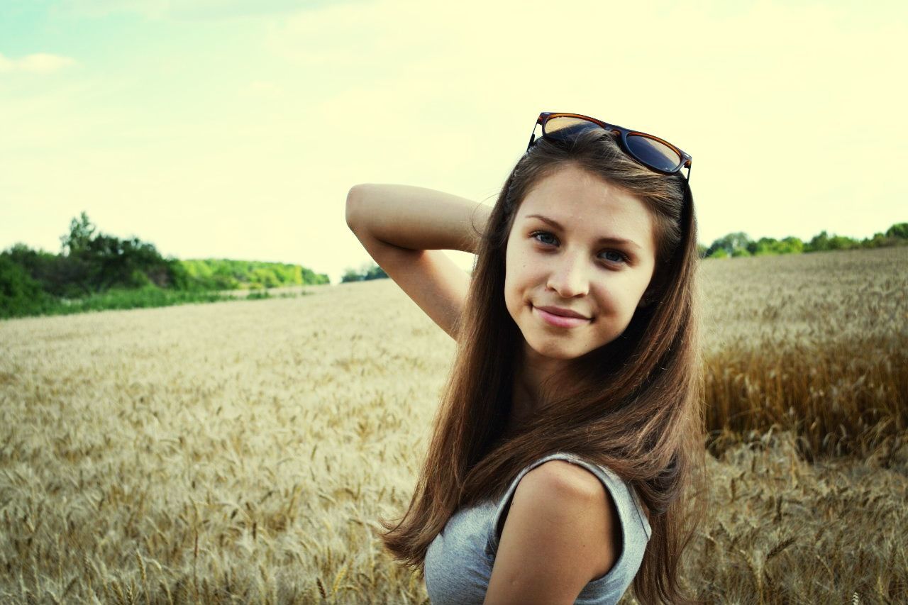 field, young adult, grass, lifestyles, person, young women, leisure activity, portrait, landscape, sky, looking at camera, grassy, casual clothing, rural scene, smiling, agriculture, front view, long hair