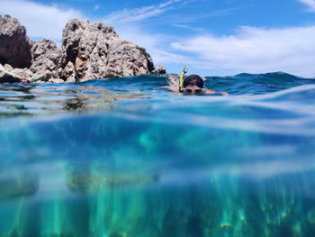 Surface level of rocks in sea against blue sky