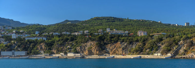 Panoramic view of townscape by sea against clear blue sky
