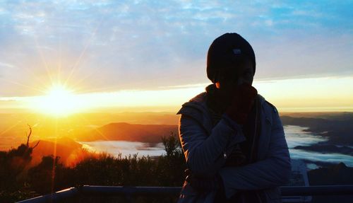 Woman standing at mount warning against sky during sunset