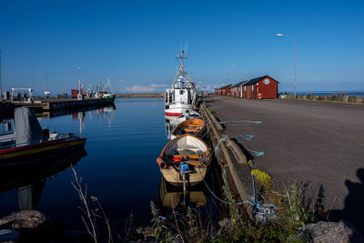 Sailboats moored at harbor against clear blue sky