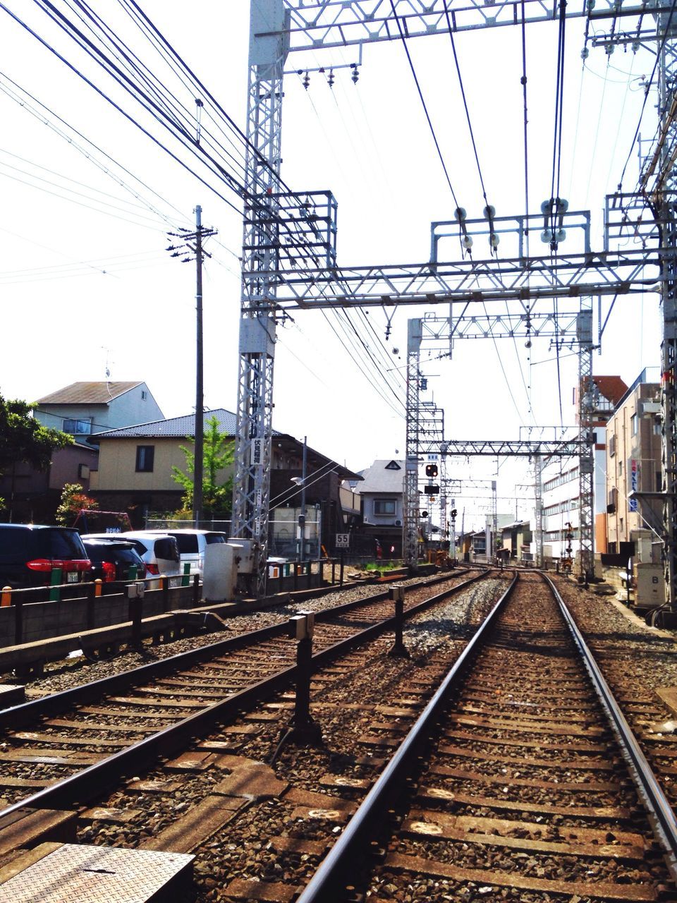 railroad track, rail transportation, power line, electricity pylon, transportation, building exterior, public transportation, power supply, railroad station, electricity, built structure, clear sky, cable, railroad station platform, the way forward, diminishing perspective, architecture, railway track, fuel and power generation, sky