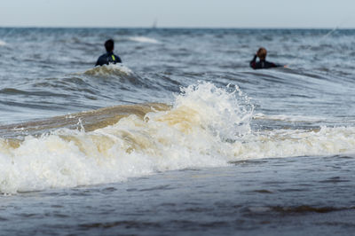 People surfing in sea against sky