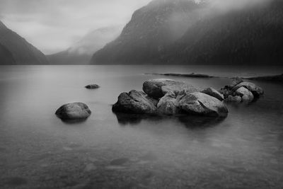 Scenic view of lake by mountains at dusk