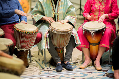 Low section of people playing djembes