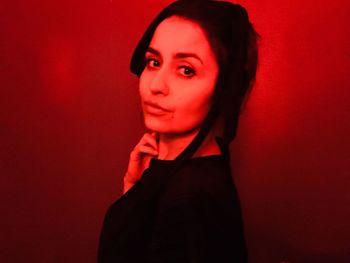 Portrait of beautiful young woman standing against red background