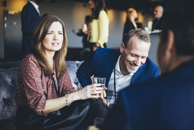 Entrepreneurs discussing while sitting with drinks in office