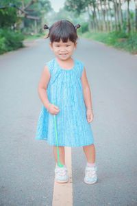 Portrait of cute girl holding toy while standing on road