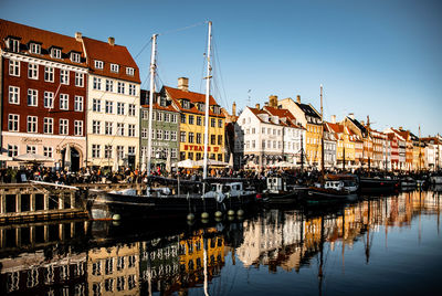 Sailboats moored on canal by multi colored buildings against sky in city