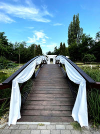 Footbridge amidst trees against sky